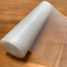 a white plastic object sitting on top of a wooden table next to a piece of paper