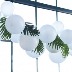 white balloons and palm leaves are hanging from the ceiling