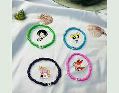 four bracelets with cartoon characters on them and seashells in the back ground