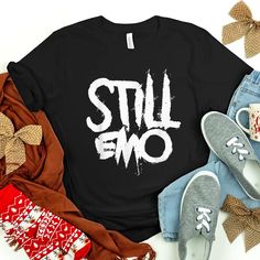 Buy Cute Still Emo Goth 80’s And 90’s Music Band Shirt at Fantasywears. Hight quality products with perfect design is available in a spectrum of colors and sizes, and many different types of shirts! Unisex T-Shirt – 100% Cotton (fiber content may vary for different colors) – Medium fabric (5.3 oz/yd² (180 g/m²)) – Classic fit – Tear away the label – Runs true to size Women T-Shirt – 100% combed ringspun cotton (fiber content may vary for different colors) – Light fabric (4.3 oz/yd² ( Fall Band Merch T-shirt With Logo, Trendy Halloween Concert T-shirt, Emo Style Fall T-shirt For Streetwear, Black Emo Fan Merchandise Top, Band Logo T-shirt For Fall Concert, Fall Concert T-shirt With Band Logo, Black Band Logo T-shirt For Fall, Cotton Emo Tops With Graffiti Print, Cotton Emo Top With Graffiti Print