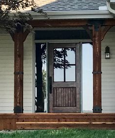 a wooden bench sitting in front of a door on top of a grass covered yard