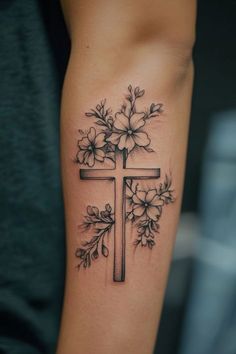 a cross with flowers on it and leaves around the cross is shown in this tattoo design