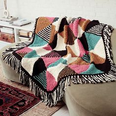 a couch with a multicolored blanket on top of it next to a rug