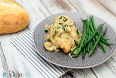 a plate with green beans and mushrooms on it next to a loaf of baguette bread