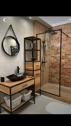 a bathroom with a sink, mirror and shower in it's stall area next to a brick wall