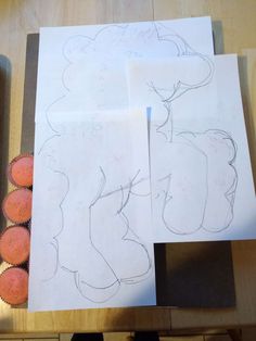 three drawings are shown on top of some paper with muffins next to them