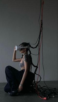 a woman is sitting on the floor with wires attached to her head and wearing a pair of gloves