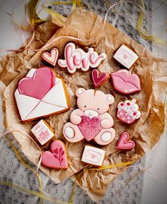 decorated cookies in the shape of hearts, teddy bears and envelopes on a table