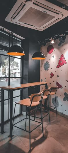 three wooden chairs sitting in front of a bar with pizza wallpaper on the walls