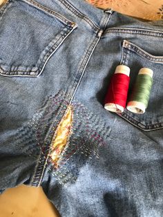 two spools of thread sit in the back pocket of an old pair of jeans