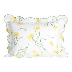 a white pillow with yellow flowers and green trimmings on the front, along with a scalloped edge