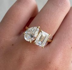 a woman's hand holding an engagement ring with two stones on the side and one stone in the middle