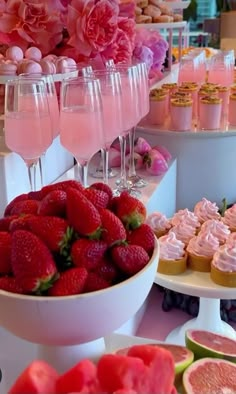 a table topped with lots of desserts and cups filled with pink frosted drinks