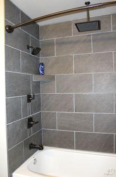 a white bath tub sitting next to a tiled wall