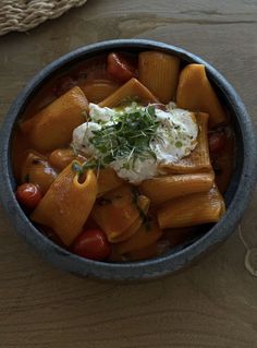 a bowl filled with pasta and vegetables on top of a wooden table