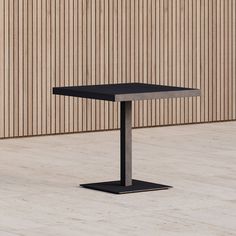 a black square table sitting on top of a wooden floor next to a tall building