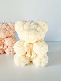 two teddy bears made out of flowers sitting next to each other on a white surface