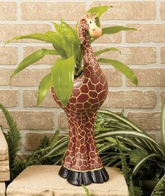 a giraffe planter sitting in front of a brick wall