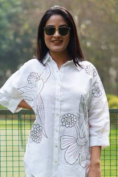 White linen shirt with contrasting flower pattern embroidery. - Aza Fashions White Floral Embroidery Relaxed Fit Top, White Floral Embroidered Relaxed Top, White Floral Embroidered Relaxed Fit Top, White Long Sleeve Blouse With Floral Applique, Relaxed Fit Tops With Floral Embroidery And Spread Collar, Summer Floral Embroidered Top With Spread Collar, Spring Linen Top With Chikankari Embroidery, Summer Top With Floral Embroidery And Spread Collar, Spring Embroidered Tops With Spread Collar