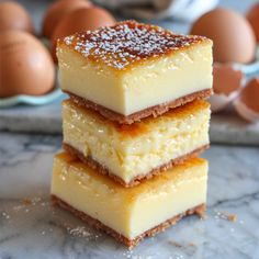 three pieces of cheesecake stacked on top of each other with eggs in the background