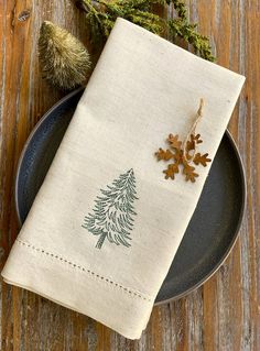 a napkin with a pine tree on it sitting on top of a plate next to an acorn