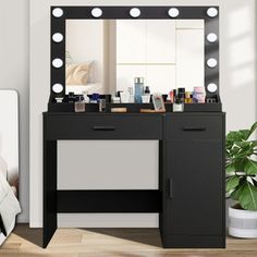 a black vanity with lights on it in front of a white chair and mirror that is next to a plant