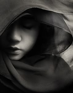 a black and white photo of a woman's face with her head covered by a veil