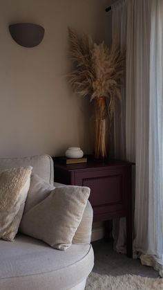 a living room with a couch, table and vase on the sideboard next to it