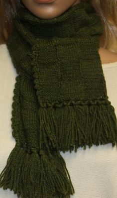 a doll wearing a green scarf with fringes on it's neck and head