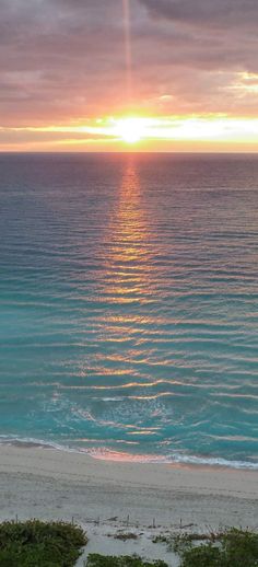 the sun is setting over the ocean and beach