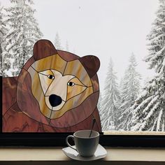 a cup and saucer sitting on a window sill in front of a painting of a bear