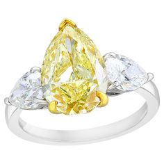 a yellow diamond ring with three pear shaped diamonds