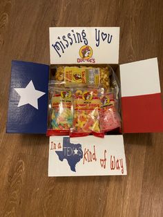 a box filled with candy and candies next to a texas flag sign that says, missing you in a kind of way