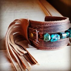 Distressed Finish Leather Cuff features a genuine strand of chunky African Turquoise. Each strand is different and will show varying shades of the natural stone. ***Please view all the pictures as they show examples of the many stone colors Cuff measures 2" by 9" in length Adjustable to 7" and 7.5" Although your item will resemble the photo, each piece is created by hand, so no two are identical.Thank you for visiting The Jewelry Junkie! Adjustable Turquoise Leather Bracelet In Rustic Style, Adjustable Rustic Turquoise Leather Bracelet, Bohemian Festival Bracelet With Patina, Southwestern Style Turquoise Leather Bracelet For Festivals, Adjustable Bohemian Cuff Bracelet With Natural Stones, Handmade Turquoise Leather Bracelet, Bohemian Style, Handmade Turquoise Leather Bracelet In Bohemian Style, Handmade Bohemian Turquoise Cuff Bracelet, Handmade Bohemian Turquoise Leather Bracelet