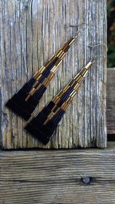 three pairs of black and gold earrings hanging from a wooden post