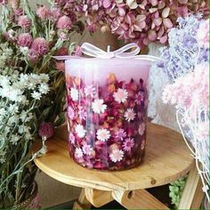 a pink candle sitting on top of a wooden table next to some purple and white flowers