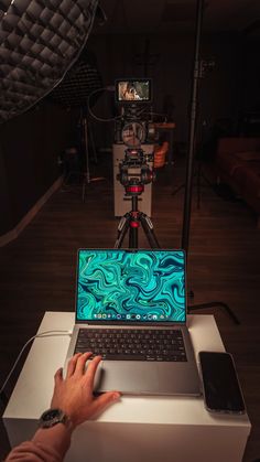 a person is using a laptop computer on a tripod in front of a camera