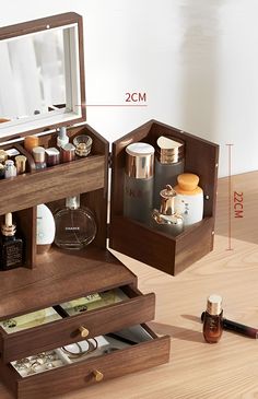 an open wooden box with cosmetics and other items inside on a table next to a mirror