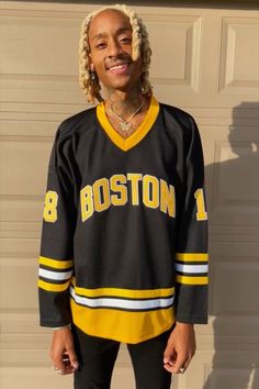 a man with dreadlocks standing in front of a garage door wearing a boston hockey jersey