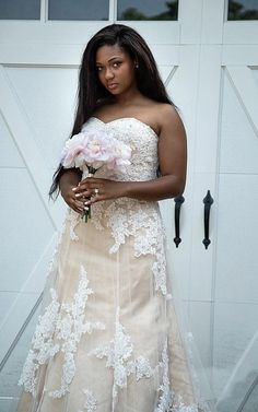 a woman in a wedding dress holding a bouquet of flowers next to a garage door