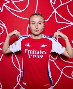 a woman poses in front of a red wall