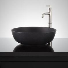 a black bowl sink sitting on top of a counter next to a faucet