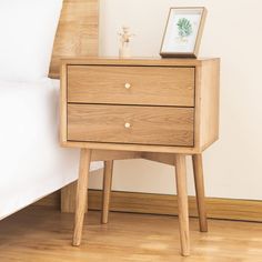 a wooden nightstand with two drawers on top of it next to a white wall and wood floor