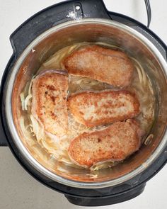 four pieces of meat are cooking in an instant pot on the stove top with noodles