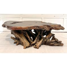 a wooden table made out of driftwood on a white floor with a door in the background