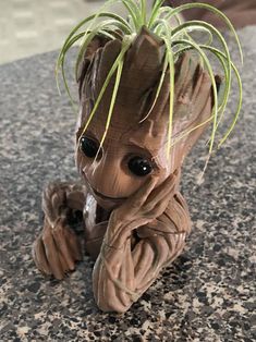 a baby groote planter sitting on top of a granite counter next to a potted plant