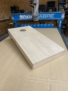 a large wooden board sitting on top of a table in a shop with other tools