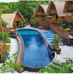 an outdoor swimming pool surrounded by grass huts