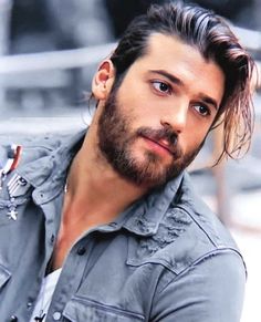 a man with long hair and a beard wearing a blue shirt looking at the camera