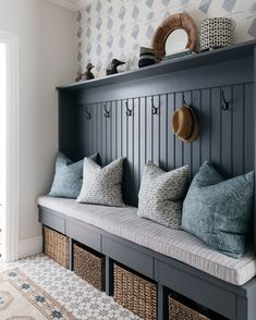 a bench with some pillows on top of it next to a wall mounted coat rack